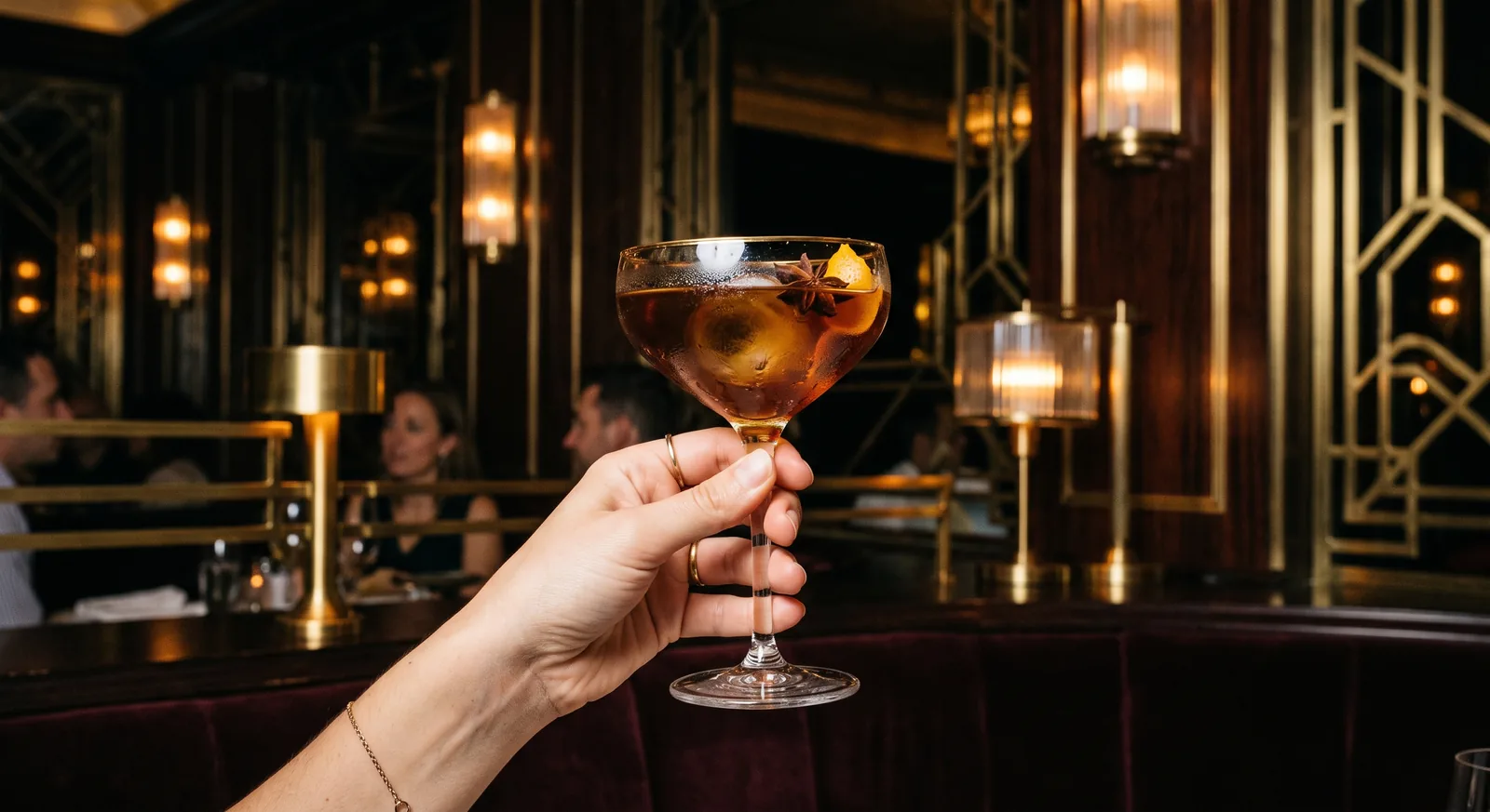 En hand håller upp en cocktail på BŒF, kvällsljus i bakgrunden.